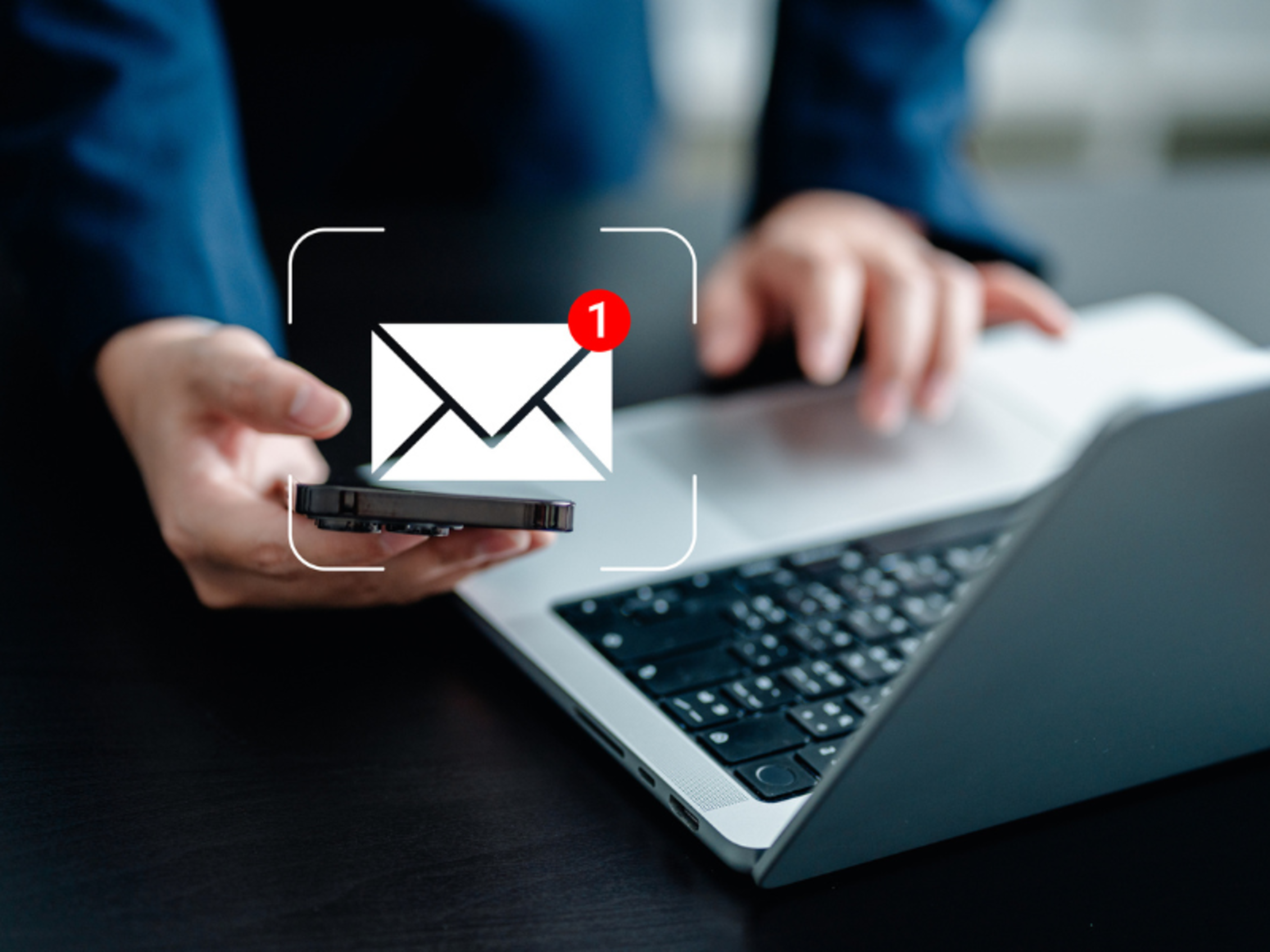 l'icona di notifica email in sovrimpressione mentre un uomo utilizza uno smartphone e un laptop